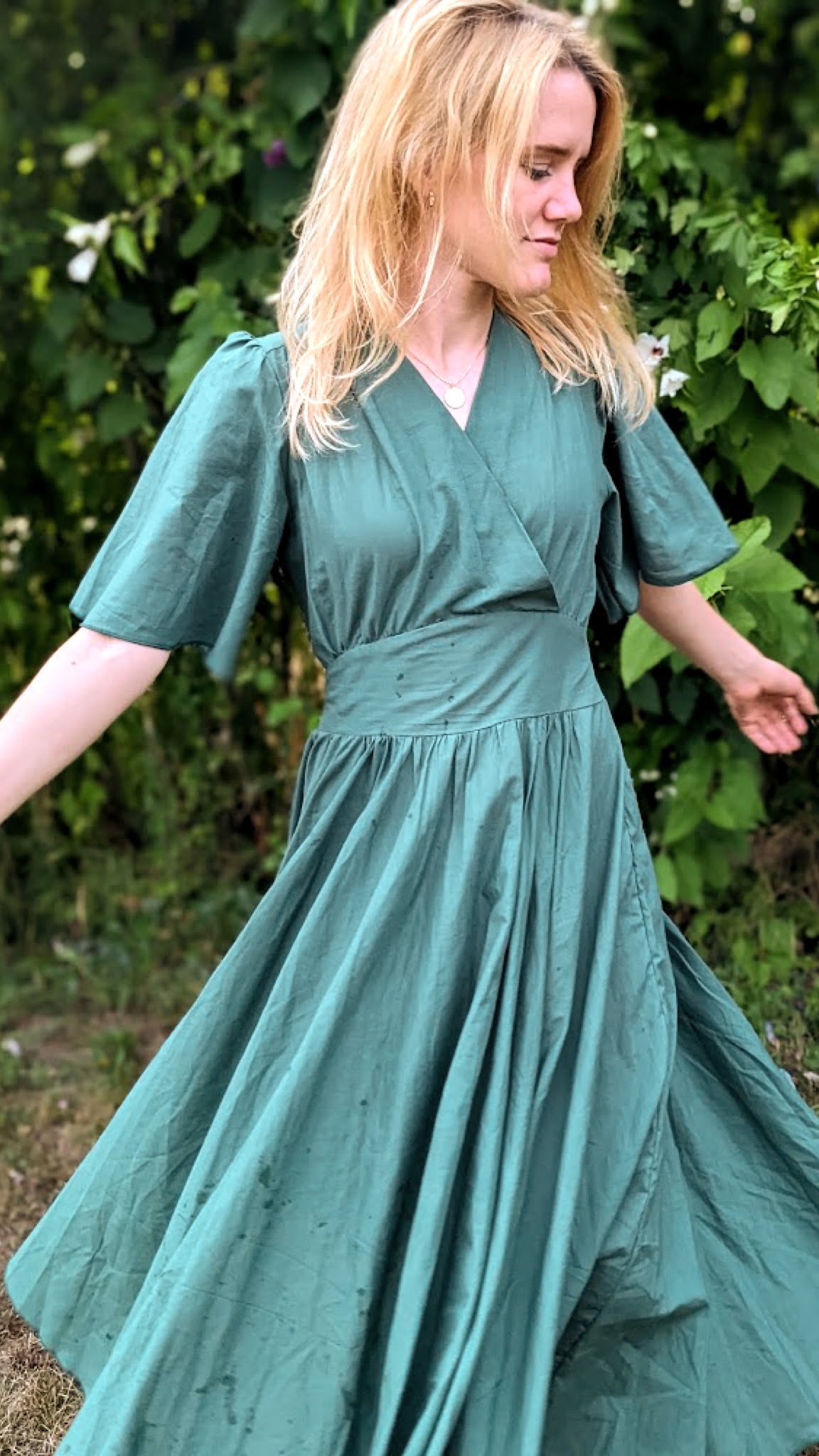 Nő sötétzöld, smaragd színű pörgős ruhában forog